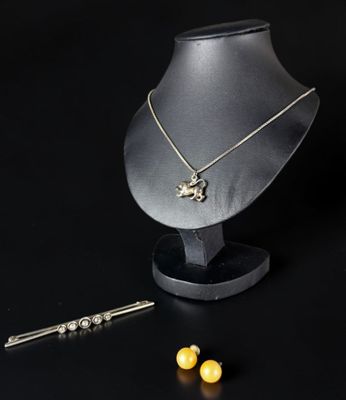 un ensemble composé d'un collier et de boucles d'oreilles posé sur un présentoir à côté d'une paire de boucles d'oreilles