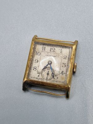 une petite montre carrée posée sur une table