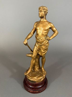 une statue antique en bronze représentant un homme tenant une épée, posée sur un socle en bois