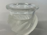 a glass vase with a leaf on it sitting on a table