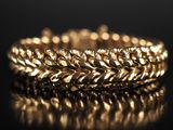 un gros plan d'un bracelet en or posé sur une surface noire