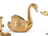 a gold swan figurine sitting next to a candle holder