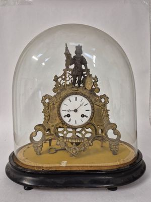 une petite horloge sous un dôme de verre sur une table