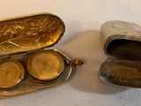 a small silver box with two coins inside of it