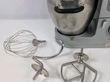 a silver mixer and a whisk on a white table