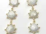 a pair of gold tone earrings with white stones on them