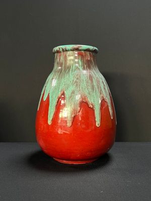 a red and green vase sitting on a table