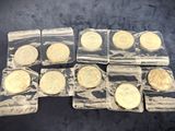 six gold coins in clear plastic bags sitting on a table