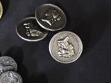 some silver buttons and some silver coins on a black surface