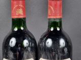 two bottles of red wine are sitting next to each other on a table