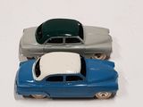 two toy cars sitting side by side on a white surface