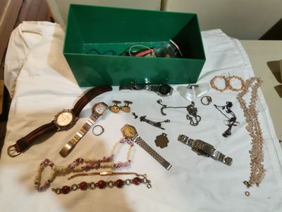 une boîte verte remplie de nombreux bijoux, posée sur une table