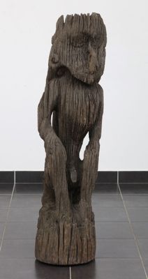 une sculpture en bois représentant un homme assis sur une souche d'arbre