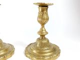 two gold candlesticks sitting on a white surface