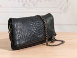 the black snake skin clutch bag is on a wooden table