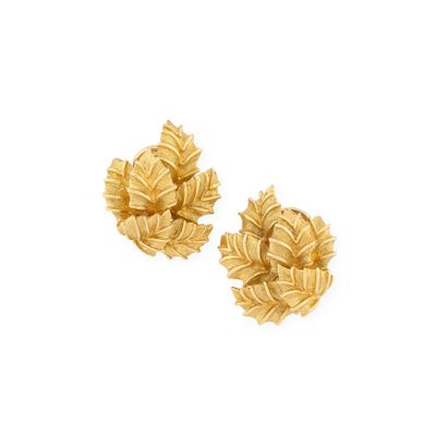 une paire de boucles d'oreilles en or ornées de feuilles sur fond blanc