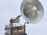 a silver gramphone on a wooden stand on a white background