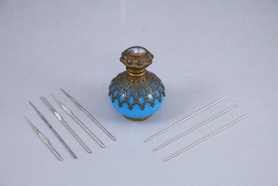 a small blue vase with needles on a white table