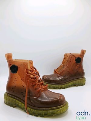 une paire de bottes marron à semelles vertes sur un fond blanc