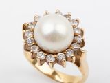 a close up of a pearl and diamond ring on a white background