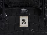 hermes ' s black crocodile skin handbag with a white and black logo on the front