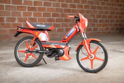 a small red motorcycle parked in front of a brick wall