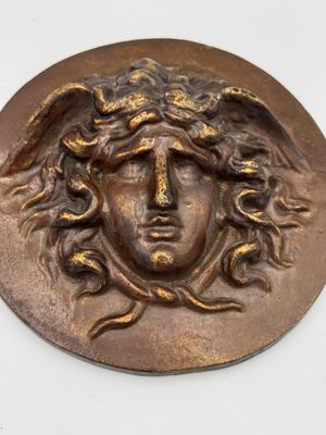 un gros plan d'un médaillon en métal sur lequel figure un visage