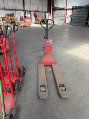 un chariot élévateur rouge et un diable rouge dans un entrepôt