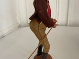 figurine of a man with a hat and cane on a white surface