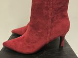 a pair of red sued ankle boots on top of a black box