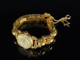 an image of a gold bracelet with a watch on a black surface