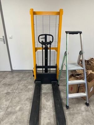 a fork lift truck parked next to a pile of wood
