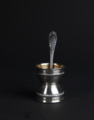 a silver spoon in a silver bowl on a black background