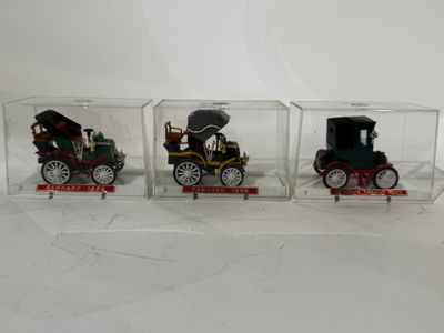 trois petites voitures miniatures se trouvent dans une boîte transparente posée sur une surface blanche