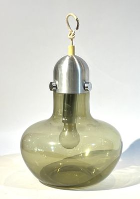 un vase en verre vert muni d'une poignée en métal, posé sur une surface blanche
