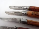 several knives are lined up on a white surface with wood handles