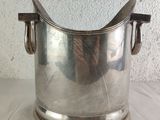 a silver ice bucket with a handle on a table
