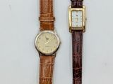 two watches are sitting next to each other on a white surface