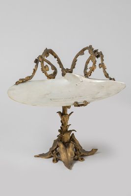 une plaque ancienne en laiton ornée d'un oiseau, posée sur un socle