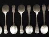 six silver spoons are lined up in a row on a black surface
