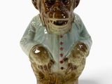 une figurine en céramique représentant un singe portant une chemise bleue