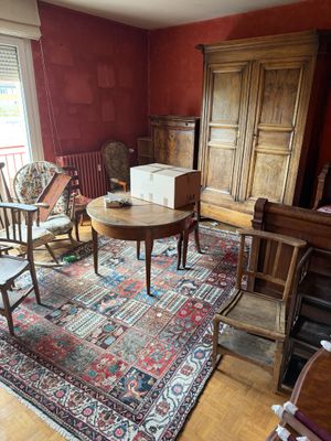 a living room with a rug, chair, table, and other furniture