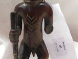 statue d'un homme tenant un bâton à la main, posée sur un socle noir
