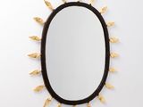 un miroir ovale noir orné de feuilles dorées et doté d'un cadre noir
