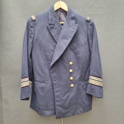a blue jacket with gold buttons on a hanger next to a wall