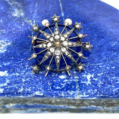 an antique silver broochle with pearls and stars on a blue stone