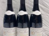 three bottles of red wine are lined up on a white surface