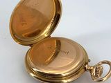 a gold pocket watch sitting on a white surface