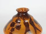 a brown and black vase sitting on a white surface