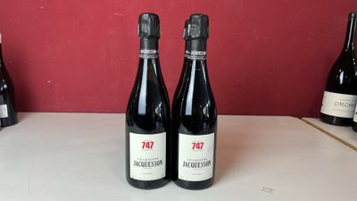 trois bouteilles de vin sont posées sur un comptoir devant un mur rouge